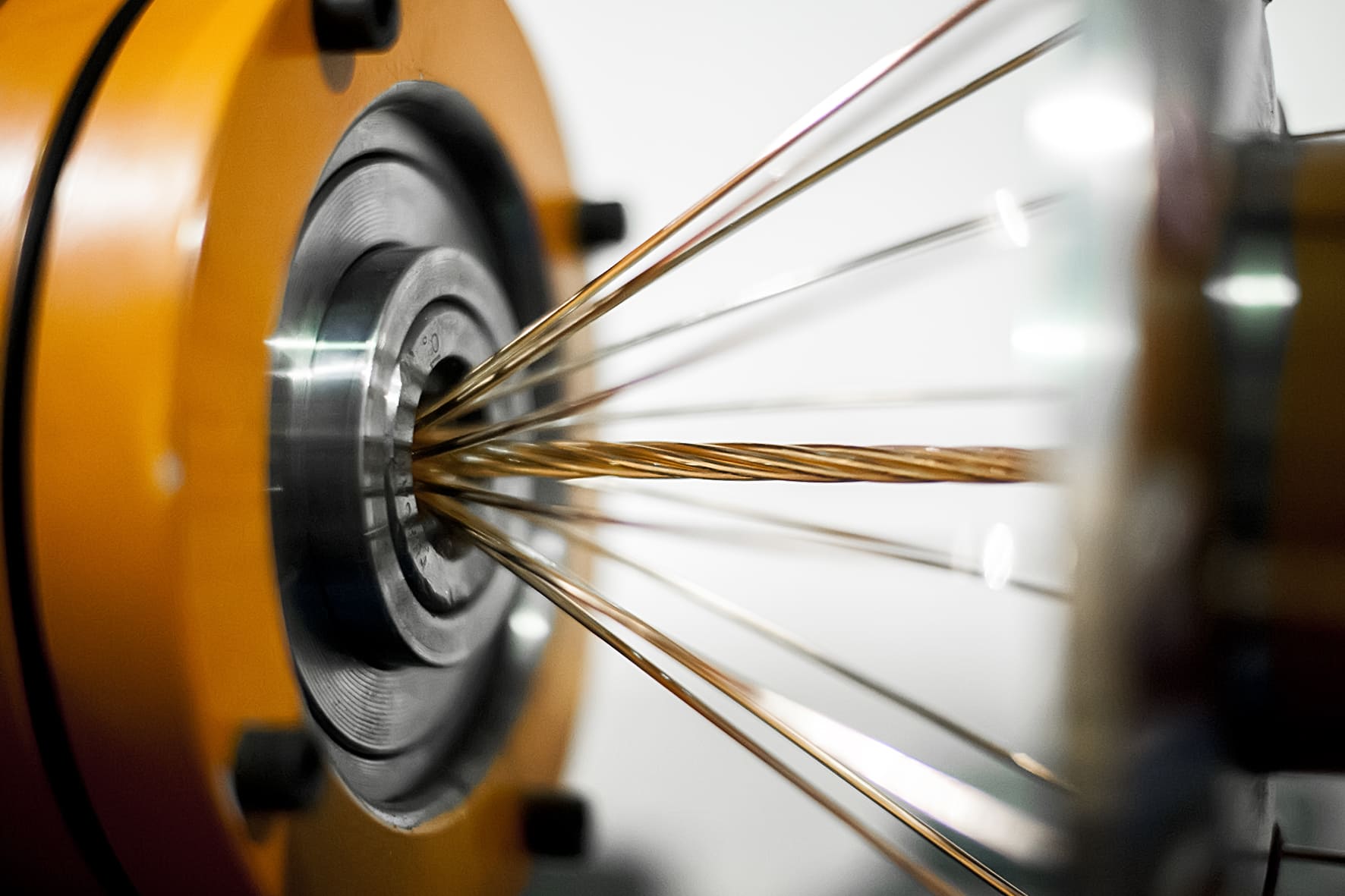 Hilos de cobre pasando a través de una matriz industrial durante el proceso de trefilado y fabricación de conductores eléctricos.