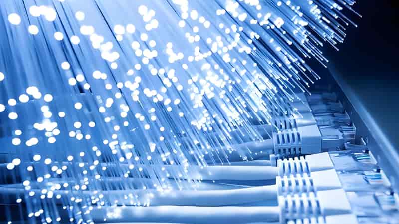Cables de fibra óptica iluminados representando conectividad, transmisión de datos y tecnología industrial avanzada